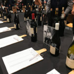 Table display of wine bottles and bid sheets at the Nedbank Cape Winemakers Guild Auction Showcase in Cape Town.